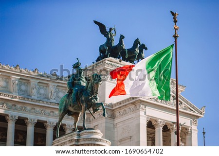 Italian flag on background on famous Vittoriano with gigantic equestrian statue of King Vittorio Emanuele II in Rome