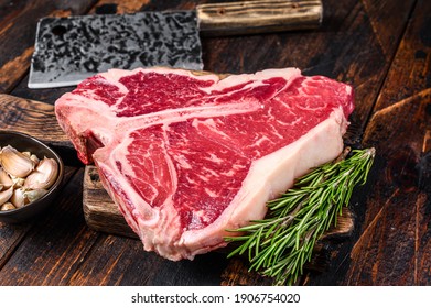 Italian Florentine T-bone beef meat Steak with herbs on a wooden cutting board. Dark wooden background. Top view