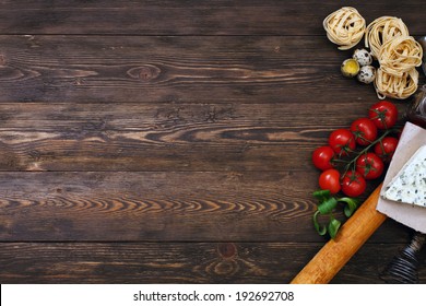 Italian Food Background On Rustic Wood Boards With Copyspace, With Tagliatelli Pasta, Tomatoes, Basil, Cheese, Grossini And Condiments