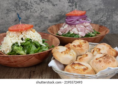 Italian Food Feast Is Set Up On The Table With Two Salads To Choose From Or A Basket Of Garlic And Cheese Rolls.