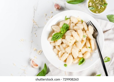 Italian food recipe, Healthy vegan dinner with potato gnocchi. With grated parmesan cheese, basil and pesto sauce. On white marble , copy space  top view