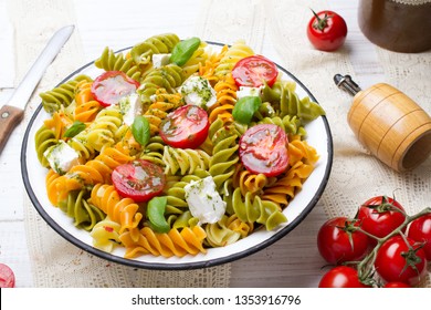 Italian food - Salad with colorful pasta, cherry tomatoes, feta cheese and fresh basil on white wooden background - Powered by Shutterstock