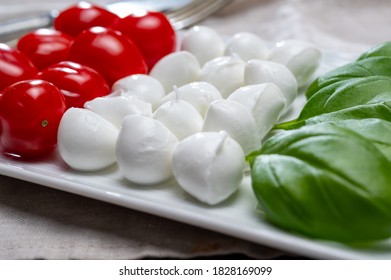 Italian food served as flag of Italy Tricolore with fresh fresh green basil, white mini mozzarella cheese and red cherry tomatoes close up