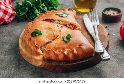 Italian food, sliced closed pizza calzone with cheese, gray stone background. Selective focus