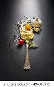 Italian Food, Spaghetti Recipe Ingredient With Vintage Fork On Black Texture Background. Overhead View. Stylized Food, Still Life Image.