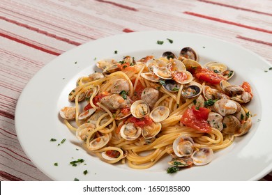 Italian Food. Typical And Delicious Spaghetti With Clams On A Table Of A Classic And Rustic Italian Tavern.