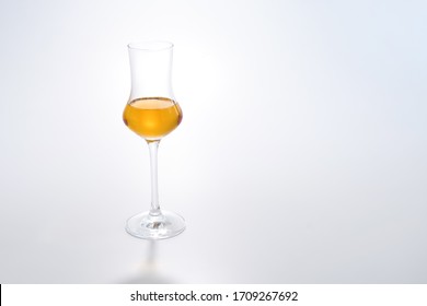 italian grape strong alcoholic drink grappa, made from the remnants of grapes after it is pressed, in the process of making wine, in a tulip-shaped glass, on a white background, horizontal frame