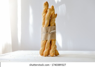 Italian grissini or salted breadsticks. sesame breadsticks in a craft paper on white wooden table. close up. artisan bread bakery - Powered by Shutterstock