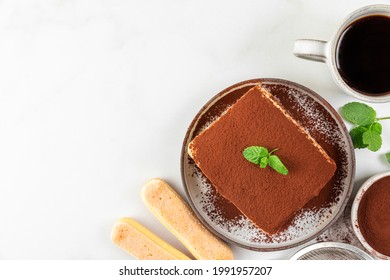 Italian homemade tiramisu cake with fresh mint on plate and coffee cup over white background. Top view with copy space. Delicious no bake dessert for tasty breakfast