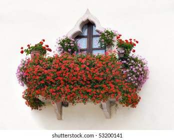 An Italian house balcony with pink and red flowers
