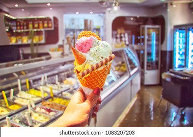 Italian Ice - Cream Cone Held In Hand On The Background Of  Shop  In Rome , Italy .It Is One Of The Best Ice Cream Place In Town Popular Among Tourists. 