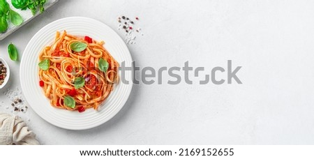Italian linguini pasta with tomato sauce and fresh basil on a gray background with space to copy. Vegetarian food. View from above.