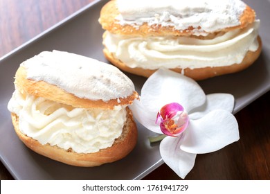 Italian Maritozzi with wipped cream and an orchid on a plate.