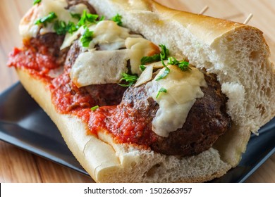 Italian Meatball Parmesan Hero Sandwich On A Torpedo Roll With Parsley Garnish