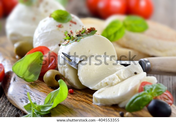 Italian\
mozzarella cheese snack with cherry tomatoes, basil and olives\
served on a wooden board with toast\
bread