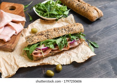 Italian panini sandwich with mortadella or Parma ham, multi grain baguette arugula and onion. Takeaway food