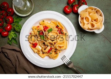 Italian pasta Calamarata made with  thick ring pasta paccheri, calamari or sliced squid, and tomato sauce.  Ingredients. Originates from Naples, the South of Italy. Directly above.