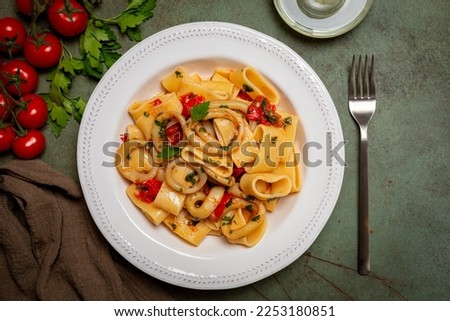 Italian pasta Calamarata made with  thick ring pasta paccheri, calamari or sliced squid, and tomato sauce.  Originates from Naples, the South of Italy. Directly above.