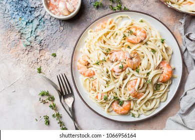 Italian pasta fettuccine in a creamy sauce with shrimp on a plate, top view - Powered by Shutterstock