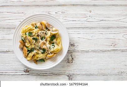 Italian pasta( fetuccini) with mushrooms, chicken meat, spinach and cream sauce on a white wooden background. Flat lay. Copy space