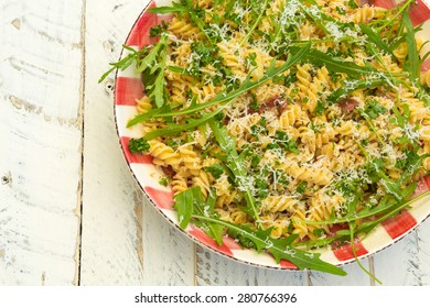 Italian pasta fusilli with fresh garlic and rocket leaves, spanish chorizo, parsley, parmesan cheese on gingham plate, white wood background - Shutterstock ID 280766396