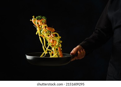 Italian Pasta With Greens And Shrimps In A Pan In A Frozen Flight On A Black Background. Sea Food. Restaurant, Hotel, Banquet, Home Cooking. Healthy Vegetarian Food, Healthy Lifestyle.