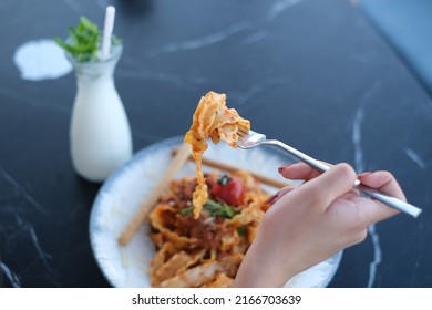 Italian pasta with meat sauce, a hand holding the pasta on a fork