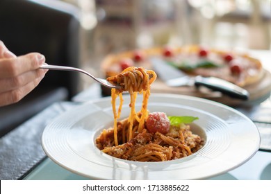  Italian Pasta On A Fork In A White Plate With Pizza In The Background