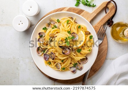 Italian pasta spaghetti with clams and lemon or Spaghetti alle vongole verace, cooked with oil, white wine, garlic, parsley. Top view.