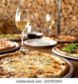 Italian pizza with cheese with glass of white wine on festive table. Dinner at pizzeria. Blurred background. Side view. - Powered by Shutterstock