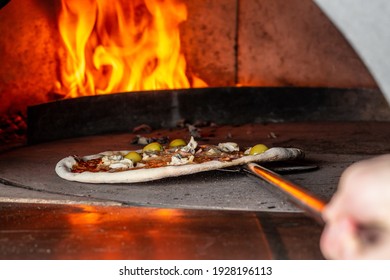 Italian pizza is cooked in a wood-fired oven. chef holding shovel for pizza, bakes dough in a professional oven.