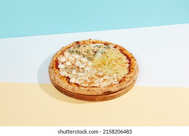 Italian pizza with four cheese on coloured background. Quattro formaggi pizza in minimal style on blue and orange color. American pizza delivery concept with color backdrop.