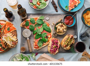 Italian pizza, hot dog grilled, salad, red wine, lager and snacks to beer, top view. Dinner table with various food for company people, top view, rustic style - Powered by Shutterstock