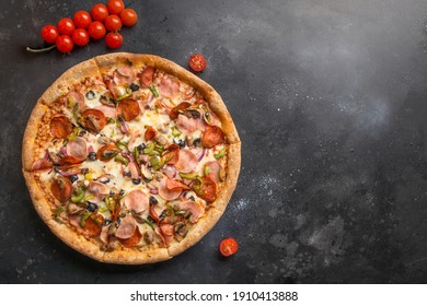Italian pizza with tomato,mushrooms, pepperoni, onion, green bell pepper, Mozzarella cheese, sauce on black. Delivery food. View from above. Copy space.