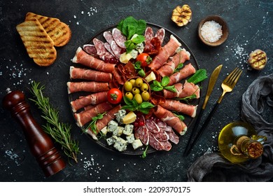 Italian prosciutto, dried pork, parmesan cheese, olives and snacks on a plate. Top view. On a gray stone background. - Shutterstock ID 2209370175