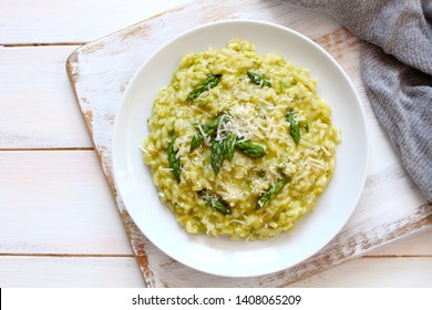 Italian risotto with spring asparagus and parmesan cheese in plate on light background. Top view with copy space.