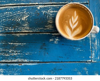 italian roasted style hot cup of coffee with latte art, urban life style refreshing drink in the morning with blue old rustic table background