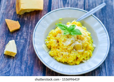  Italian  saffron risotto milanese  with parmesan cheese and fresh basil on rustic background