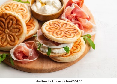 Italian Sandwich. Tigella, Prosciutto, Italian Crudo Ham, Soft Cheese And Rocket Salad. Tigelle Are Thin Round Breads From The Emilia-Romagna, Northern Italy Food. Close-up.