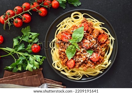 Italian spaghetti bolognese on plate over black stone background. Top view, flat lay