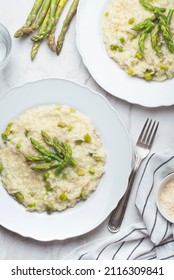 Italian spring light risotto with asparagus and Parmesan cheese on a white marble background. Spring recipes with asparagus, top view