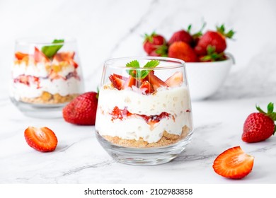 Italian strawberry tiramisu dessert with mascarpone and whipped cream, savoyardi crumb and fresh strawberry in glass on marble. Recipe of simple dessert, cheesecake, pudding or berry trifle cake.