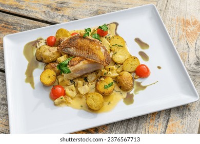 Italian style grilled skate wings on artichoke ragout and trilled potatoes on a old wooden table