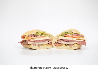 An Italian Sub Sandwich Sliced In Half Portraying All Of Its Ingredients On A White Background