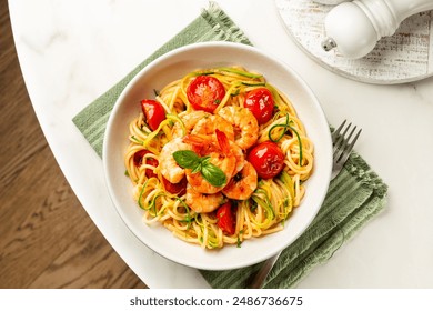 Italian summer seafood pasta directly above. Prawn, tomato and courgette, or zucchini, spaghetti in a white plate on a round marble table. - Powered by Shutterstock