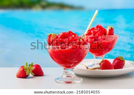 Italian summer sweet fruit food. Strawberry granita Siciliana, a semi-frozen dessert.  Sea view on background.