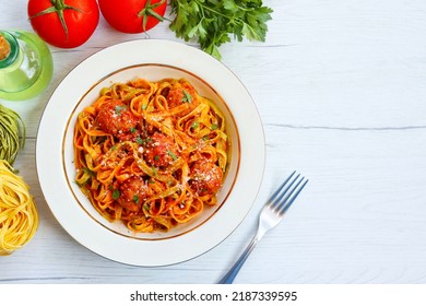 Italian Traditional Dish"Paglia e fieno con polpettine",spinach and eggs fettuccine pasta with meatballs in tomato sauce on bowl with white wood table background.Top view.Copy space - Powered by Shutterstock