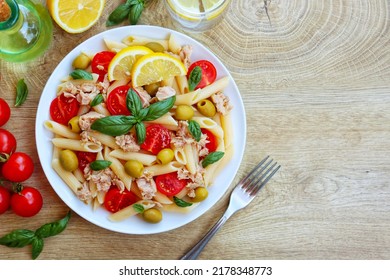 Italian Traditional Dish"Pasta fredda con tonno,pomodorini e olive",pasta salad with canned tuna,cherry tomatoes and olives on plate with wooden table background.Healthy Italian summer salad.Top view
 - Shutterstock ID 2178348773