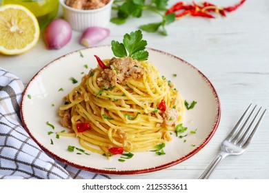 Italian Traditional Dish"Spaghetti al tonno e limone",spaghetti with tuna in olive oil,lemon juice,shallots,olive oil,hot peppers and parleys on plate with white wood background.Copy space - Shutterstock ID 2125353611