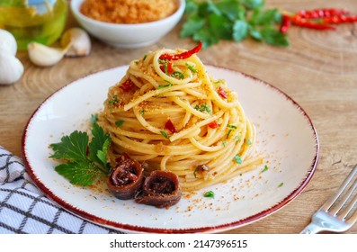 Italian Traditional Dish"Spaghetti con acciughe e pangrattato",spaghetti with anchovy,roasted breaf crumbs,garlics,olive oil,chilli peppers and parleys on plate with wooden background.Copy space

 - Shutterstock ID 2147396515